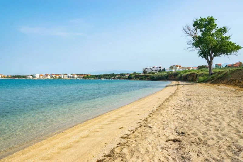 Sandstrand Perilo mit flachem, klarem Wasser in Povljana